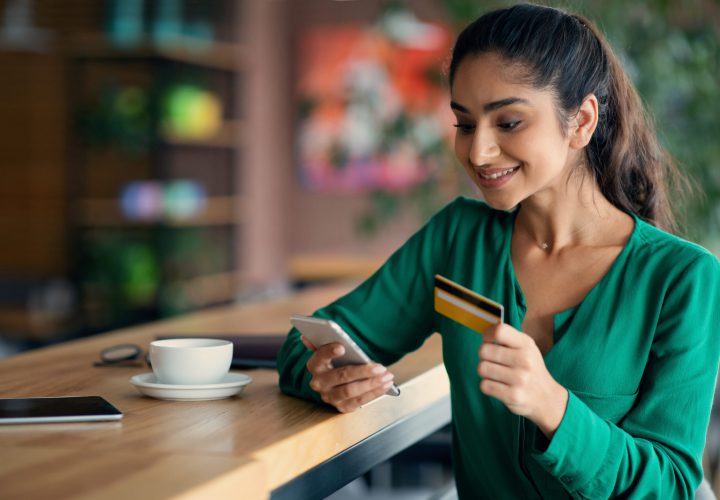 Happy young lady using mobile phone and credit card