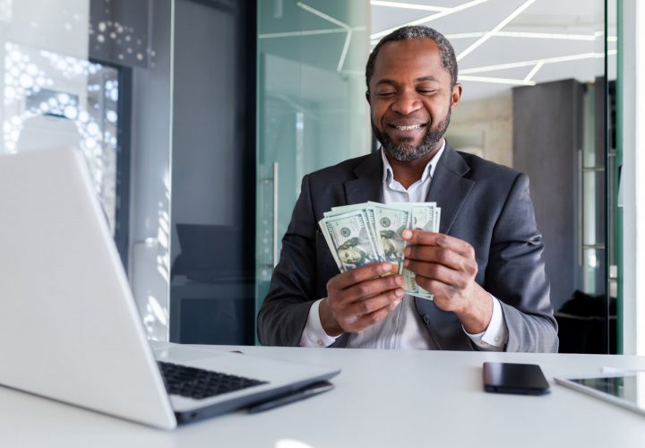 Businessman joyful got win profit income, man counts money US dollars cash inside office at